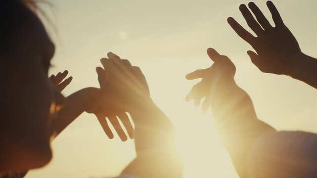 happy family people group pull hands to the sun teamwork. silhouette people party dancing recreation holiday. people at a music concert pull their hands up. religion lifestyle sunlight concept