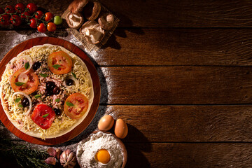 Various vegetables at wooden rustic background with copyspace on round pizza desk. Set of fresh vegetables. Egg, tomatoes, pepper, lettuce, onion, garlic, onion. Pizza ingredients.