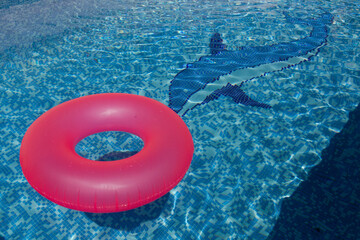 Flotador rosa flotando en el agua cristalina de una piscina azul con un delfín en un verano caluroso en España foto tomada a mediodía 