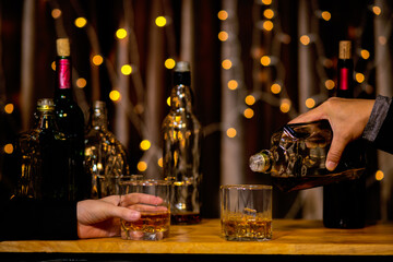 Waitress man standing pours whiskey into a glass 