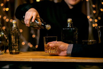 Barman pouring whiskey glass beautiful night