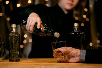 Barman pouring whiskey glass beautiful night