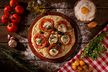 Fototapeta na wymiar Various vegetables at wooden rustic background with copyspace on round pizza desk. Set of fresh vegetables. Egg, tomatoes, pepper, lettuce, onion, garlic, onion. Pizza ingredients.
