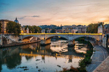 Tiber river with illuminated bridge in Rome evening at sunset, Italy.