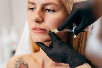 Doctor in gloves  giving woman injections in lips