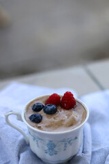 Banana nice cream with berries, served in a vintage cup. Selective focus.