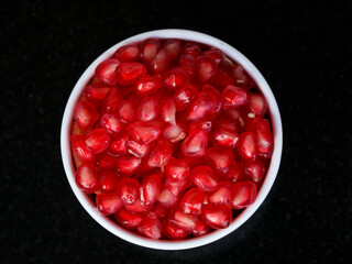 Fresh red color pomegranate kernels in a white bowl