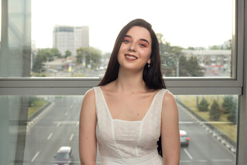 Portrait of a beautiful brunette in a light dress on the street in a pedestrian crossing on a summer day