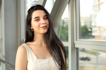 Portrait of a beautiful brunette in a light dress on the street in a pedestrian crossing on a summer day