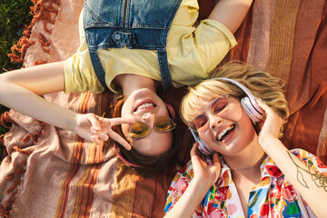 Image of two women gesturing peace sign and using wireless headphones