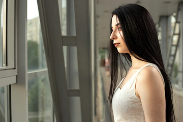 Portrait of a beautiful brunette in a light dress on the street in a pedestrian crossing on a summer day