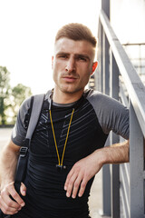 Image of sportsman looking at camera while bending over railing