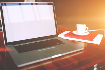 Portable laptop computer with copy space screen for your text message or advertising content, open net-book and cup of coffee lying with notepad on a wooden table in a contemporary interior