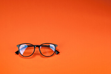 Different types of glasses on an orange background close up. Glasses with round frames. Layout for...