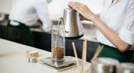 Close-up. young woman pouring hot water into a glass to make herbal tea