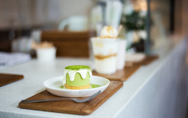 Close-up of green tea cake on white plate with cream cheese and green tea powder on top