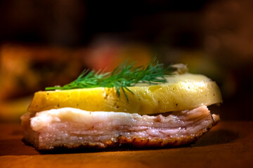 Sandwich, lard and on top potatoes with fried skin and on top parsley in the rays of light