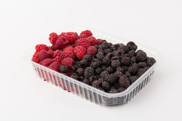 Fresh black and red raspberry in  plastic container isolated on white background. Berry in close-up
