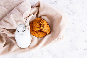 Milk in a glass bottle and slices of oatmeal cookies on a linen napkin. The concept of home breakfast and healthy eating. Top view.