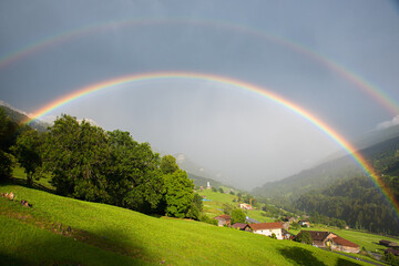 doppelter Regenbogen mit Blick nach Saas im Prättigau, Schweizer Alpenlandschaft Graubünden