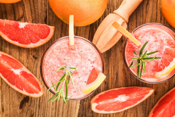 Grapefruit juice with rosemary and ice in a glass on the table. Refreshing summer cocktail