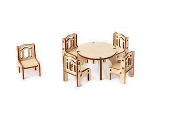 A toy miniature wooden furniture set stands. Dining table and four chairs. Furniture for dolls and dollhouse.