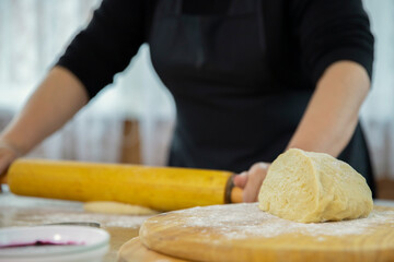 Close up female hands kneading yeast dough on table sprinkled with flour, woman baker cooking roll of baking dough. Making pizza, bread, pie - homemade pastry products. Nature, food, bio and diet
