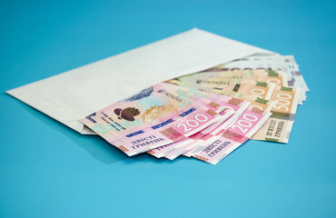 Ukrainian hryvnia in a white envelope isolated on a blue background. 200, 500, 1000 hryvnias. Financial concept.