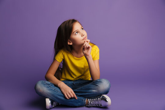 Photo of thinking cute girl looking upward while sitting on floor