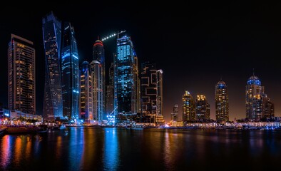 Fototapeta na wymiar Illuminated Modern Buildings By River Against Sky At Night