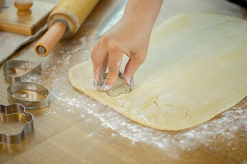 Close up woman baking sugar cookies for Christmas, saint valentines day. Holiday season baking. Female baker makes shortbread cookies with shape of heart and flowers using metal molds. Handmade pastry