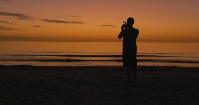 495 Man taking a picture of the sunset at the beach