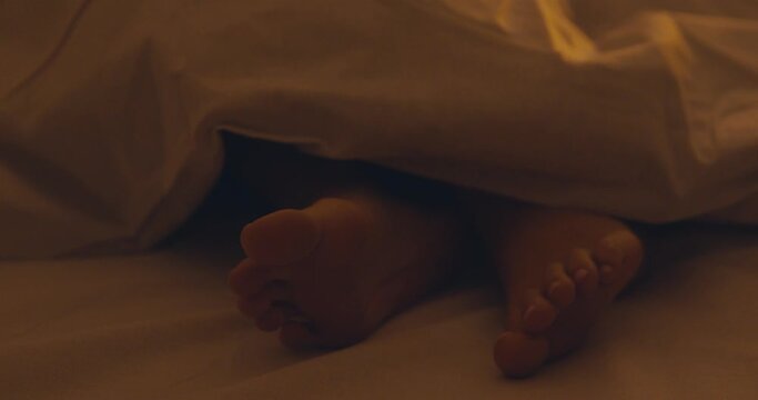 Close up of female feet under blanket, girl sleeping in bed