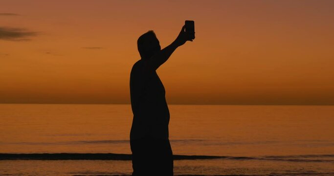 496 Silhouette of a man taking a selfie during sunset at a beach