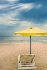 vacation spot with yellow umbrella on an empty beach without people during travel and tourism industry crisis, marine environment pollution problem, concept of virus spread on earth