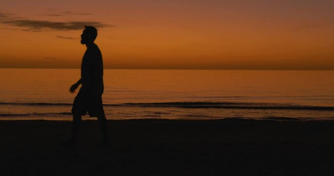 497 Silhouette of a man walking on a beach during a sunset