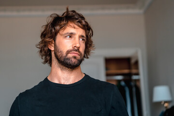 Street style with a young brunette caucasian man in a black suit and a white shirt in a luxurious hotel. Nervous in the preparations for the big wedding event