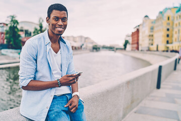 Half length portrait of handsome cheerful hipster guy chatting in social network with followers via...