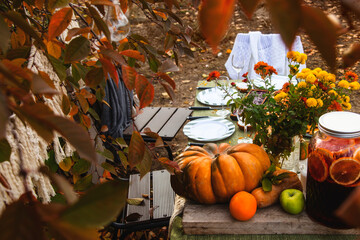 Naklejka na ściany i meble A festive autumn brunch among the yellow trees, with pumpkins, a yellow bouquet and pastries. Thanksgiving or family dinner in the backyard.