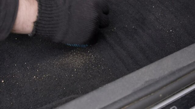 A male cleaner vacuuming the pile on the car floor from the sand. Regular vacuum cleaning textile inside the vehicle. Hoovering car interior and cleaning service concept. Close up