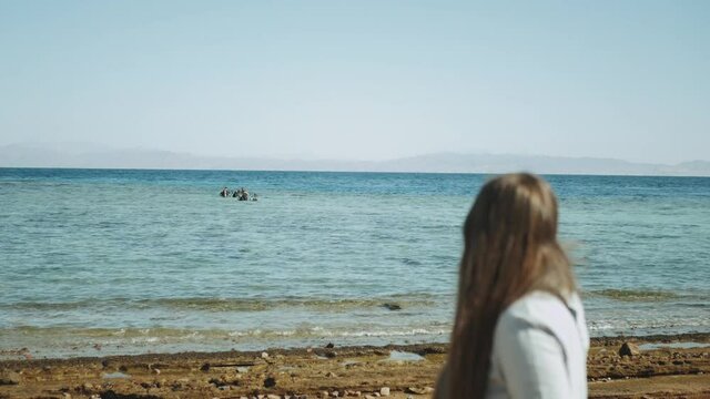 Woman looks how a group of people in diving lessons learn to dive in red sea, sunny day and clear water in Dahab, Egypt , full hd