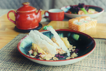 Maki rolls, fried shrimps and tea on table, toned