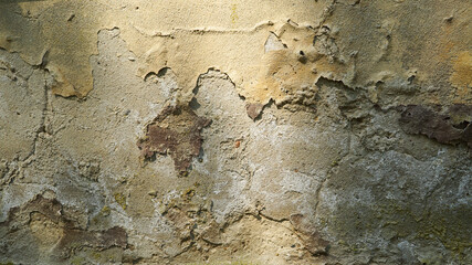 Old yellow ancient wall with peeling plaster; old concrete wall