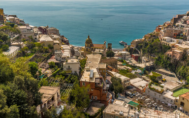 Fototapeta na wymiar The domed church and pastel coloured buildings stretch down to the sea at Positano on the Amalfi coast, Italy