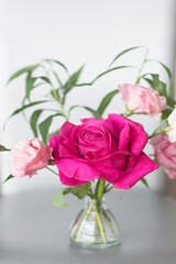 Bouquet with a pink rose on a light vertical background.