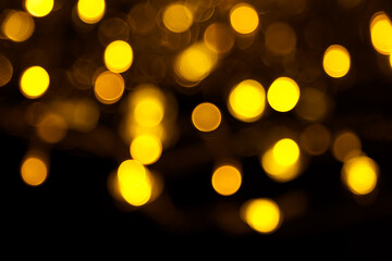 Abstract gold bokeh on black background. Defocused yellow lights, abstract texture