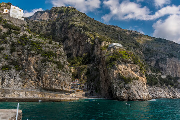 Fototapeta na wymiar A deep ravine in the rocky coastline houses the settlement of Marina di Praia, Praiano, Italy