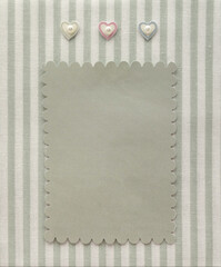 Retro style album page with blank photo and hearts decoration on vintage striped pattern textile