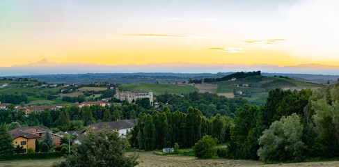Fototapeta na wymiar costigliole d'asti town, view of the castle at dust sunset with monviso alps in background. Langhe monferrato wine region, piedmont, Italy