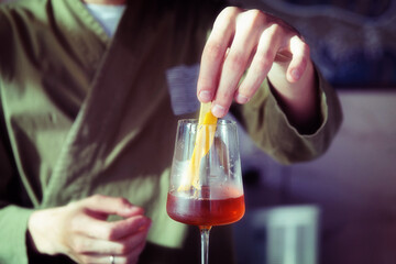 Male bartender is adding lemon zest to cocktail, toned